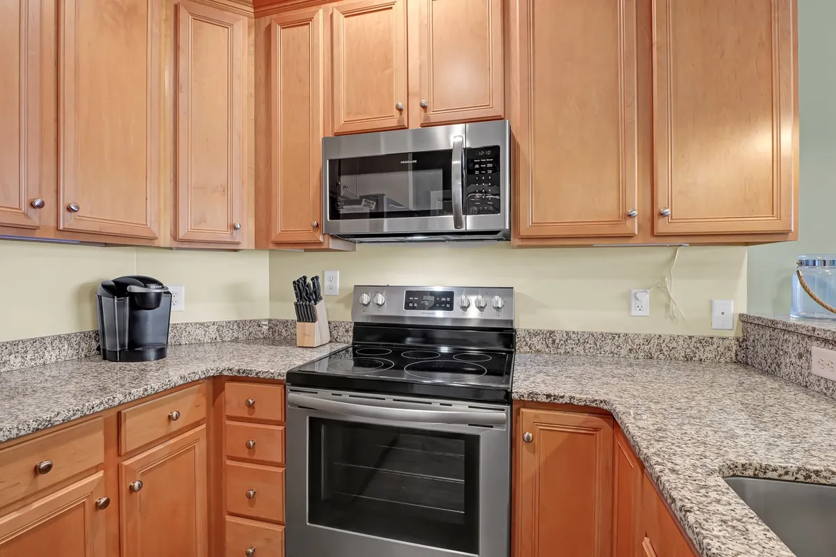 This image features a modern kitchen with granite countertops, stainless steel appliances, and wooden cabinets, exuding a sense of functionality and warmth. The scene hints at meal preparation, entertaining, and family gatherings, making it a central hub for self-catering and flexible living.