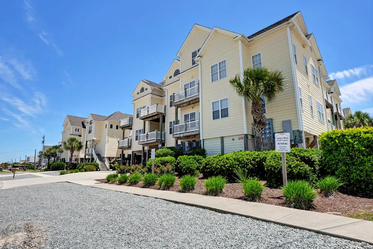 The hero image features a bright yellow condo building framed by swaying palm trees, with inviting balconies that overlook sunset vistas. The cheerful exterior and lush grounds suggest a welcoming, laid-back coastal atmosphere, ideal for relaxation and exploration.