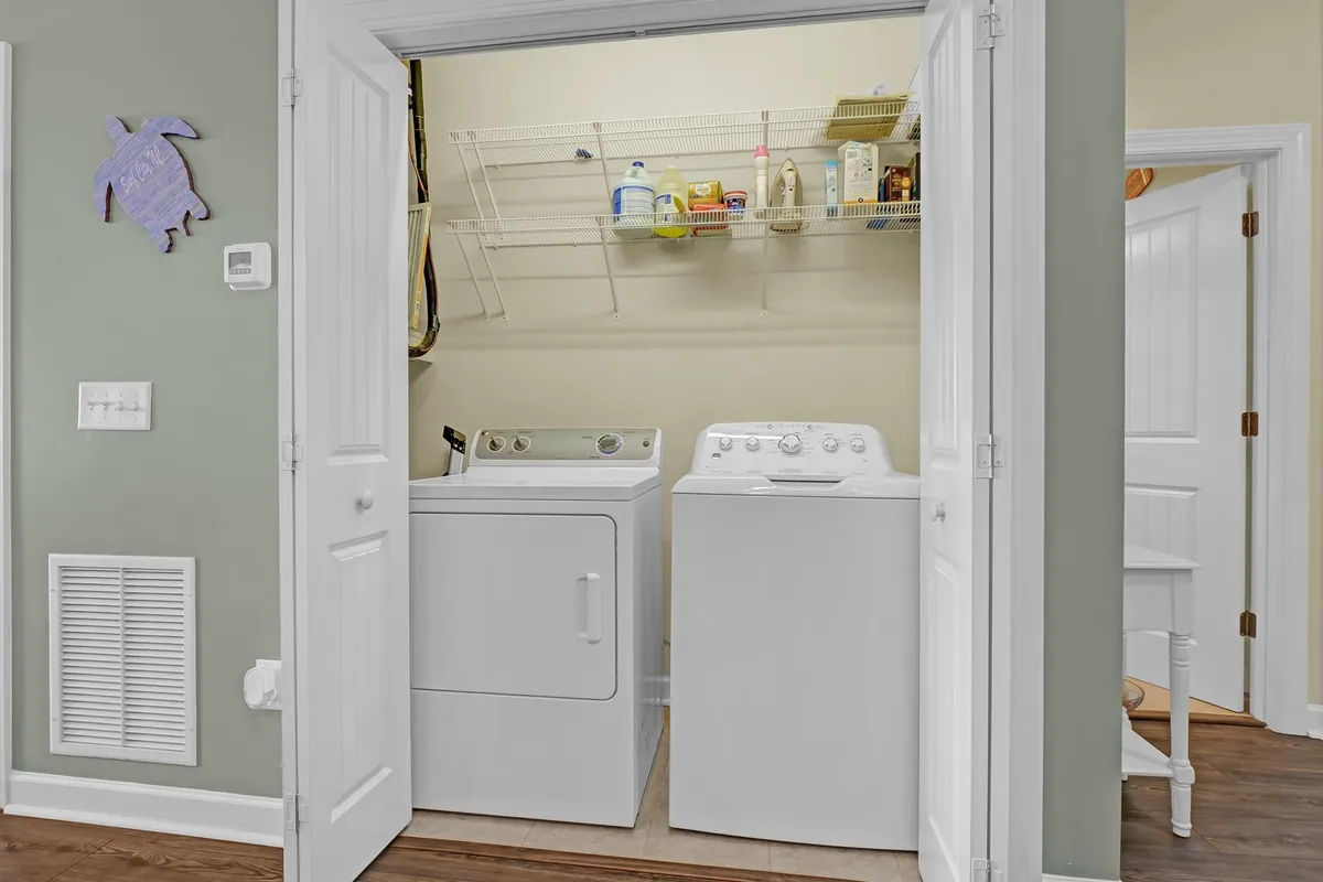 A well-organized laundry area with a washing machine, dryer, shelf for supplies, and playful turtle decoration. The tidy space underscores the practical amenities available for guests who want to manage their own comfort and routines.